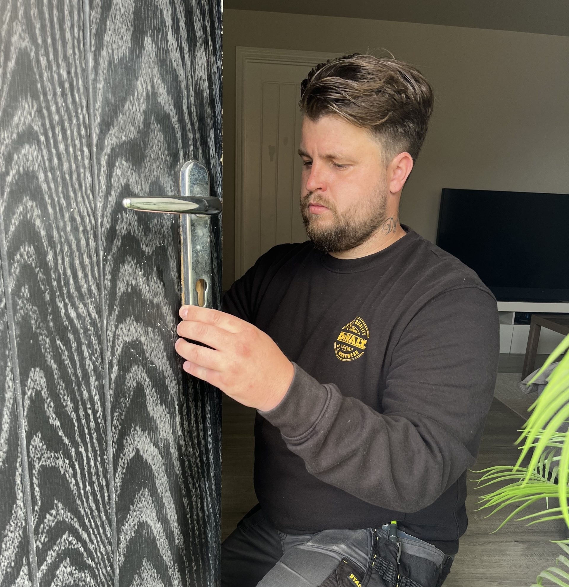 Connor from Seymour Locksmiths inspecting a lock on a black front door